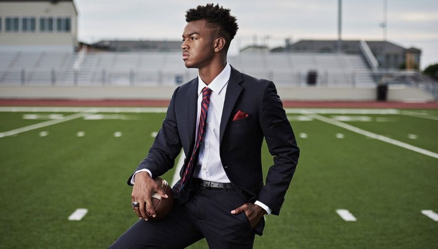 a young man holdi a football on pose.