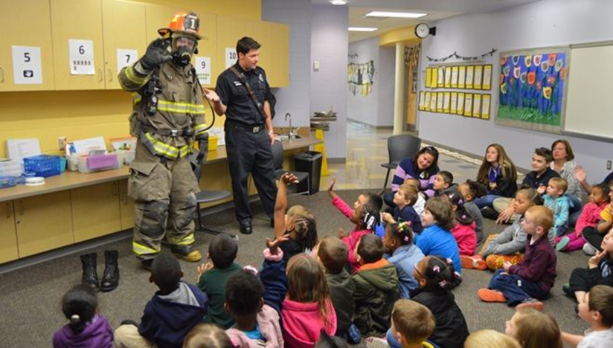 Image of a fireman officers and students sitting on the floor