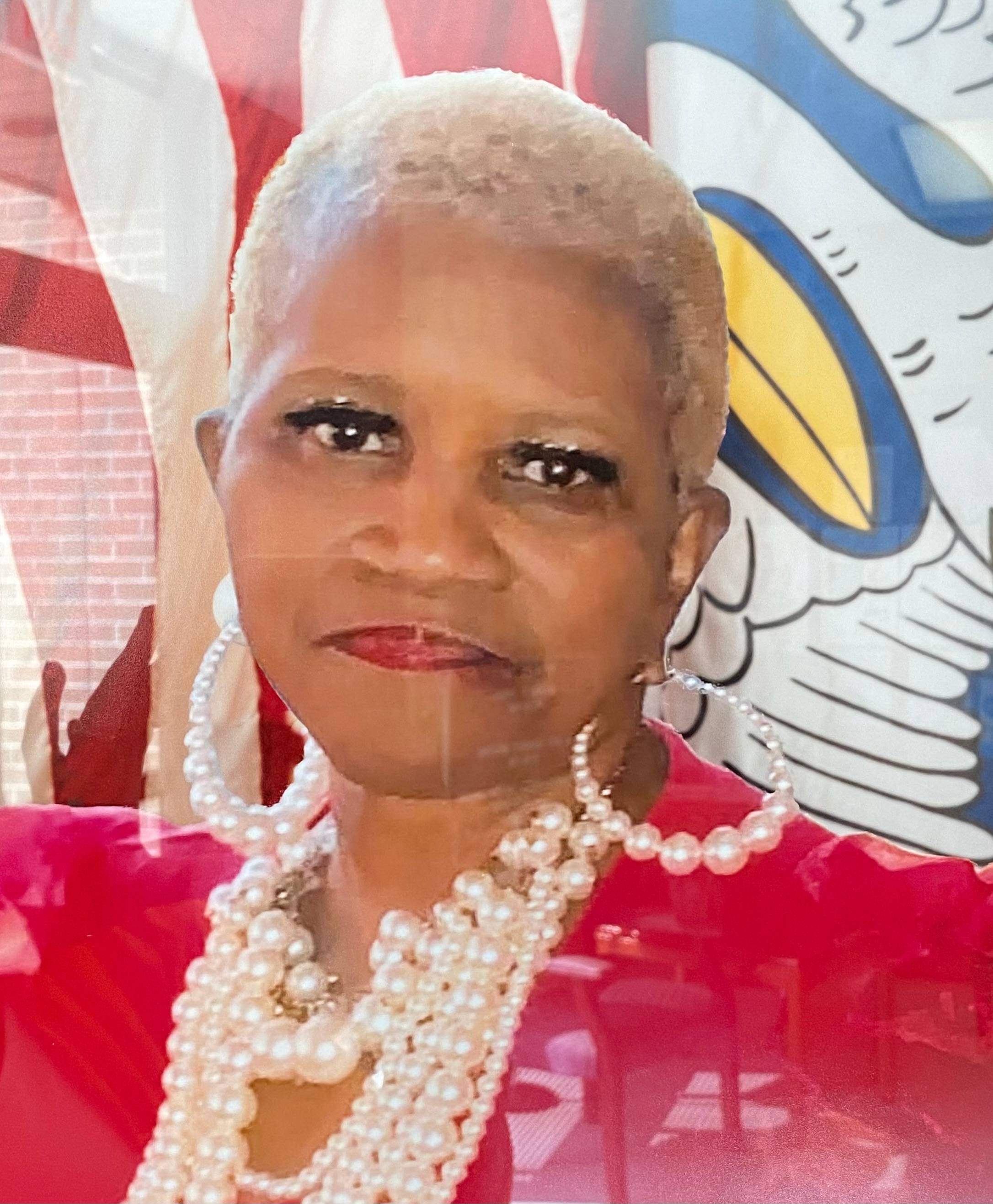 A woman wearing a red dress and pearls.