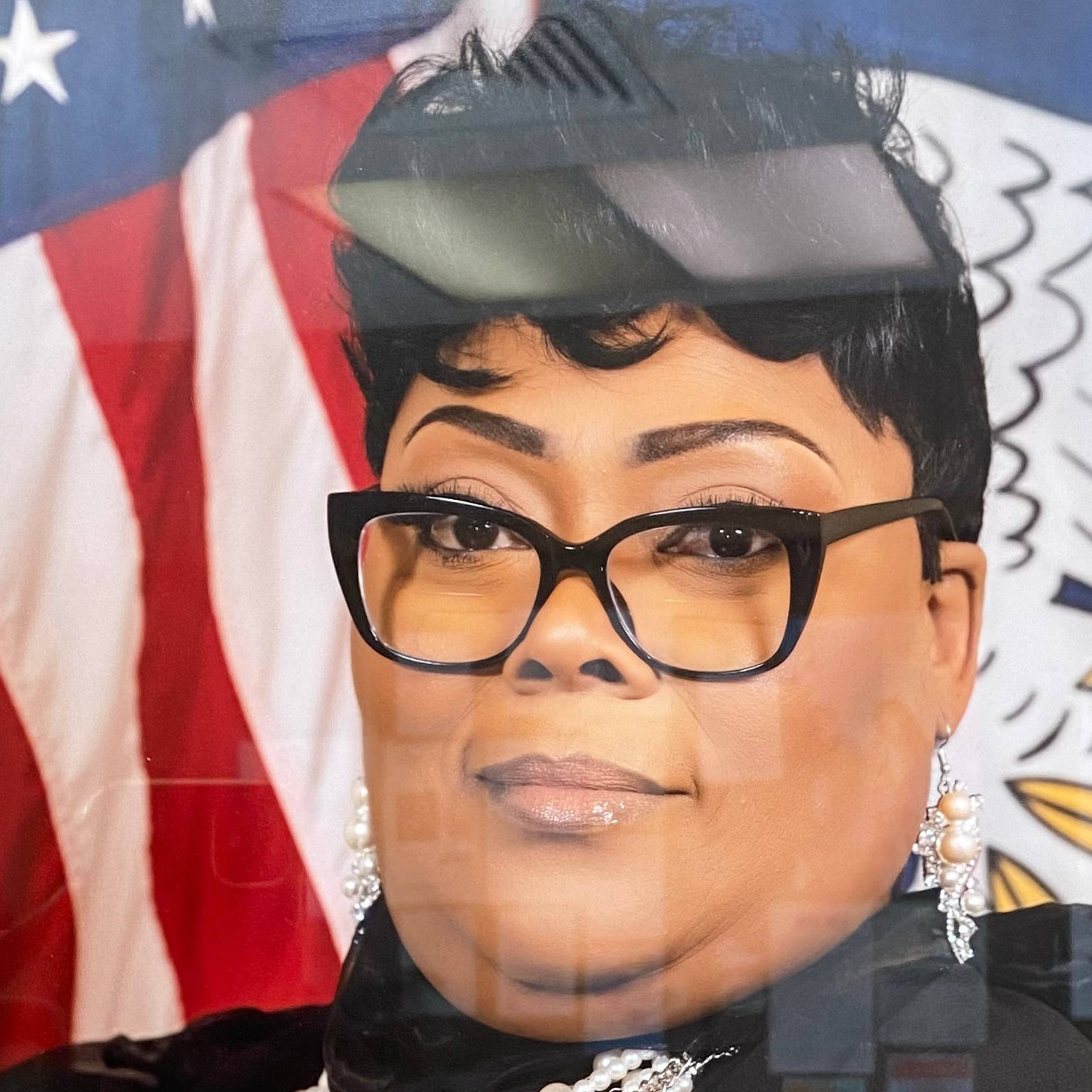 Woman in glasses and black dress with American flag design.