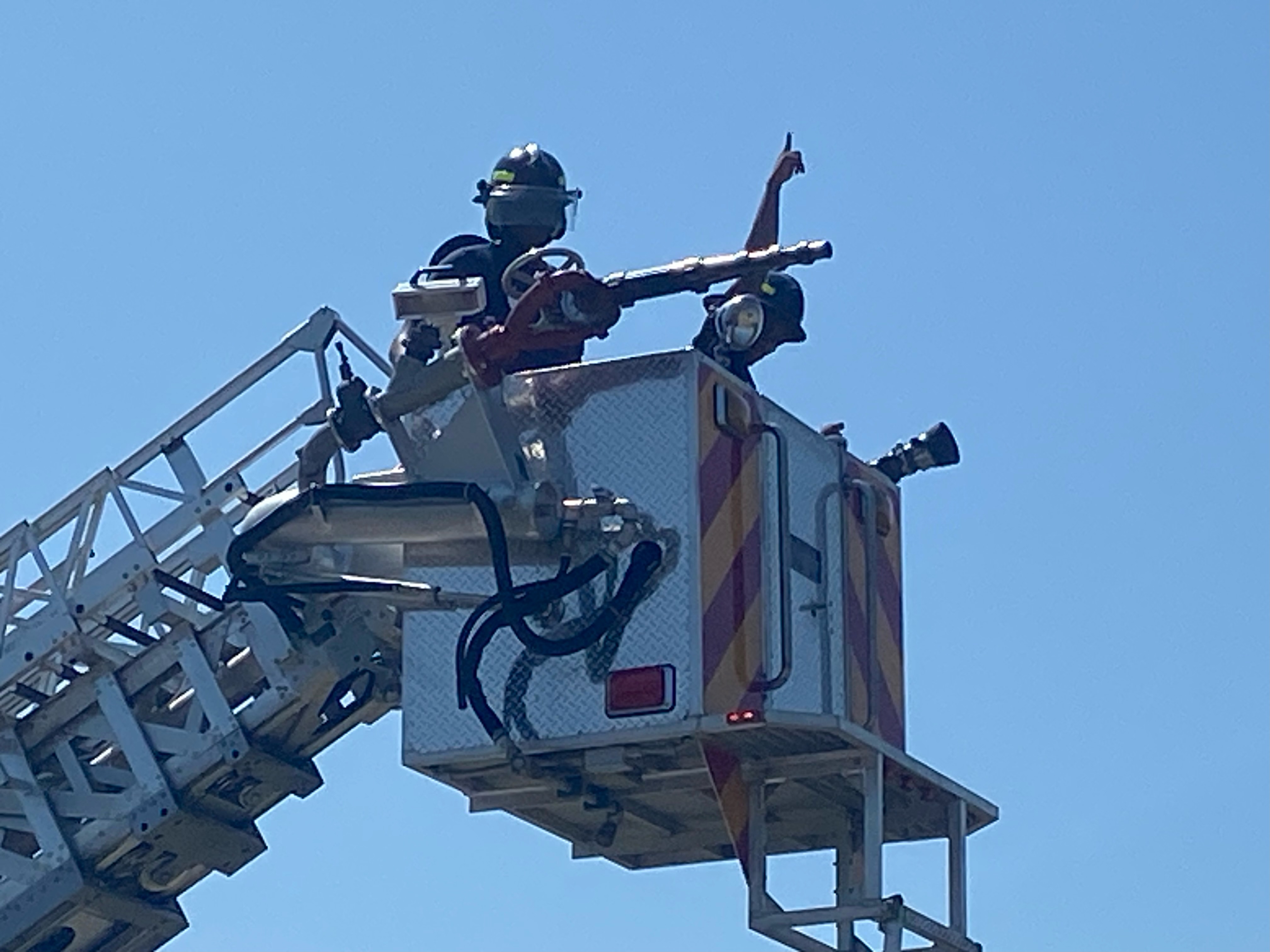 A firefighter stands on top of a ladder truck, ready to respond to an emergency situation.