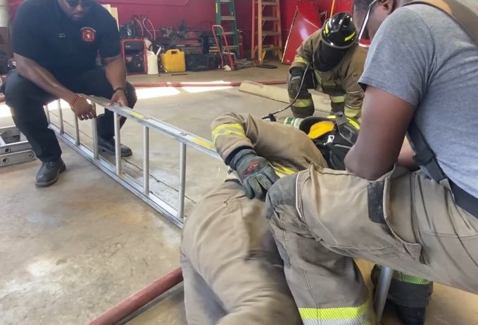 Firefighters on ladder in garage, battling flames with teamwork and precision.