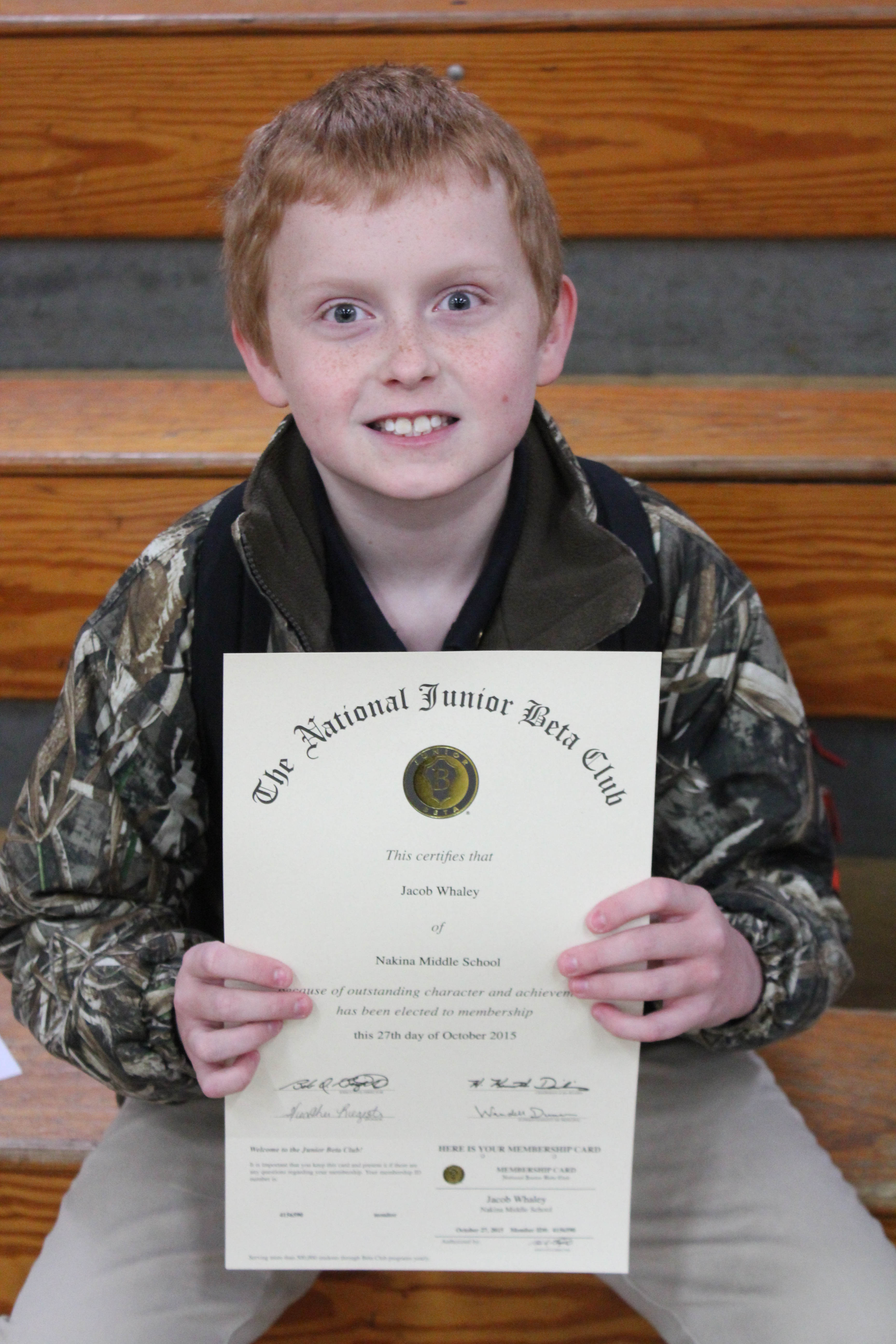 A young boy proudly displaying a certificate of achievement.