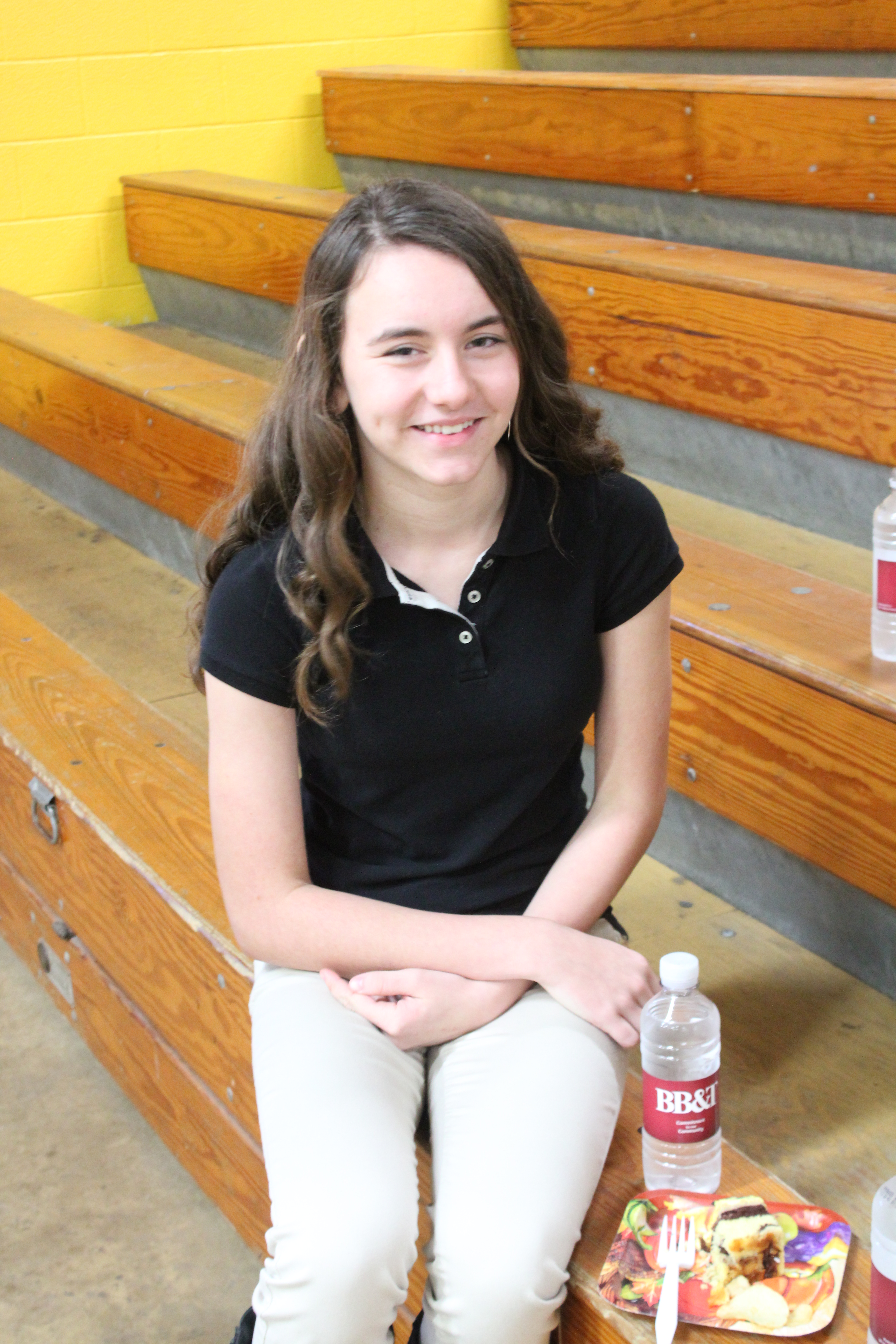 A young woman sitting on a wooden bench in a park.