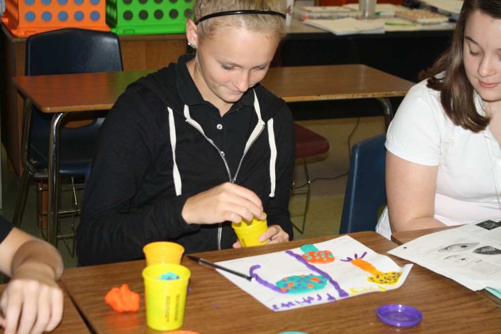 Children at elementary school molding clay sculptures in art class.