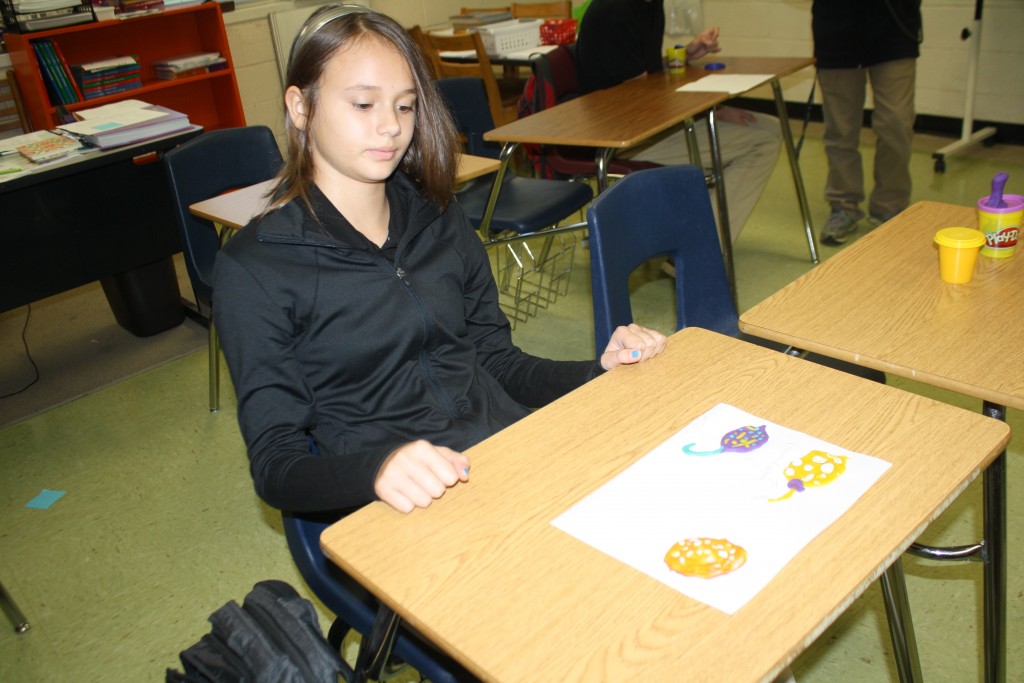 A girl sitting at a desk with a drawing of a flower on it.