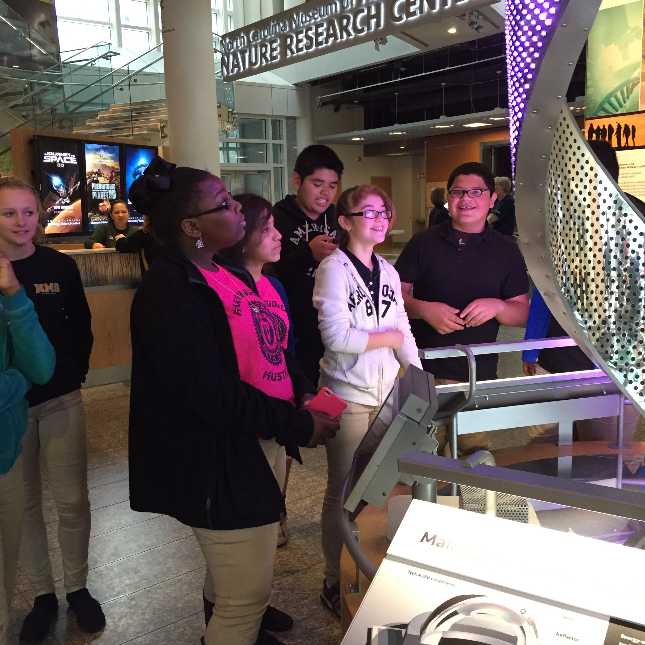 A diverse group of individuals observing a big screen together.