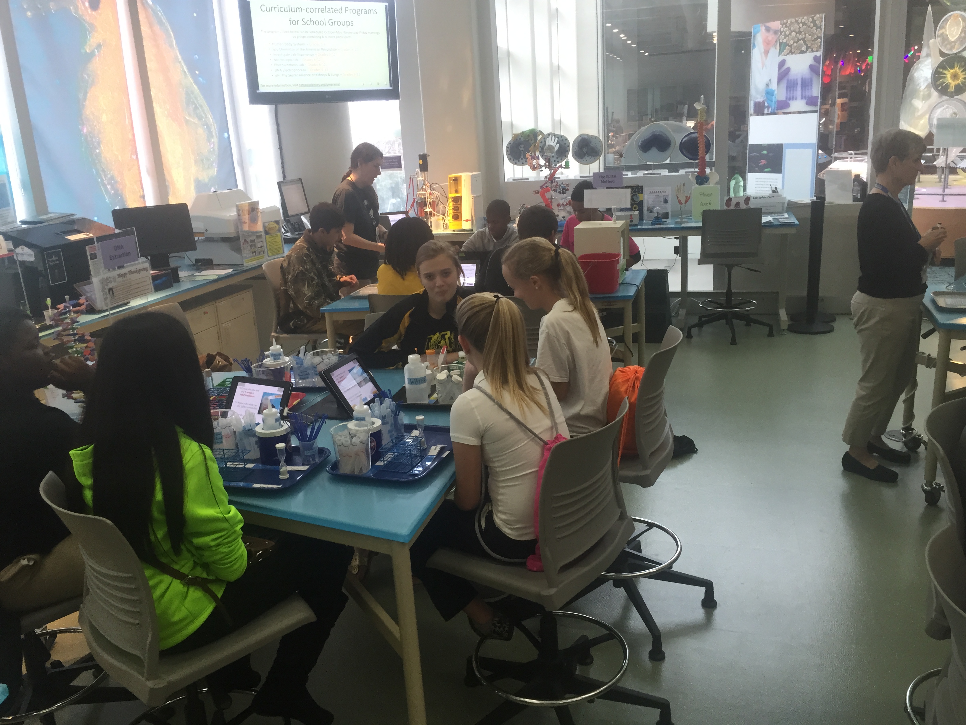 A classroom with students sitting at tables, engaged in learning activities.