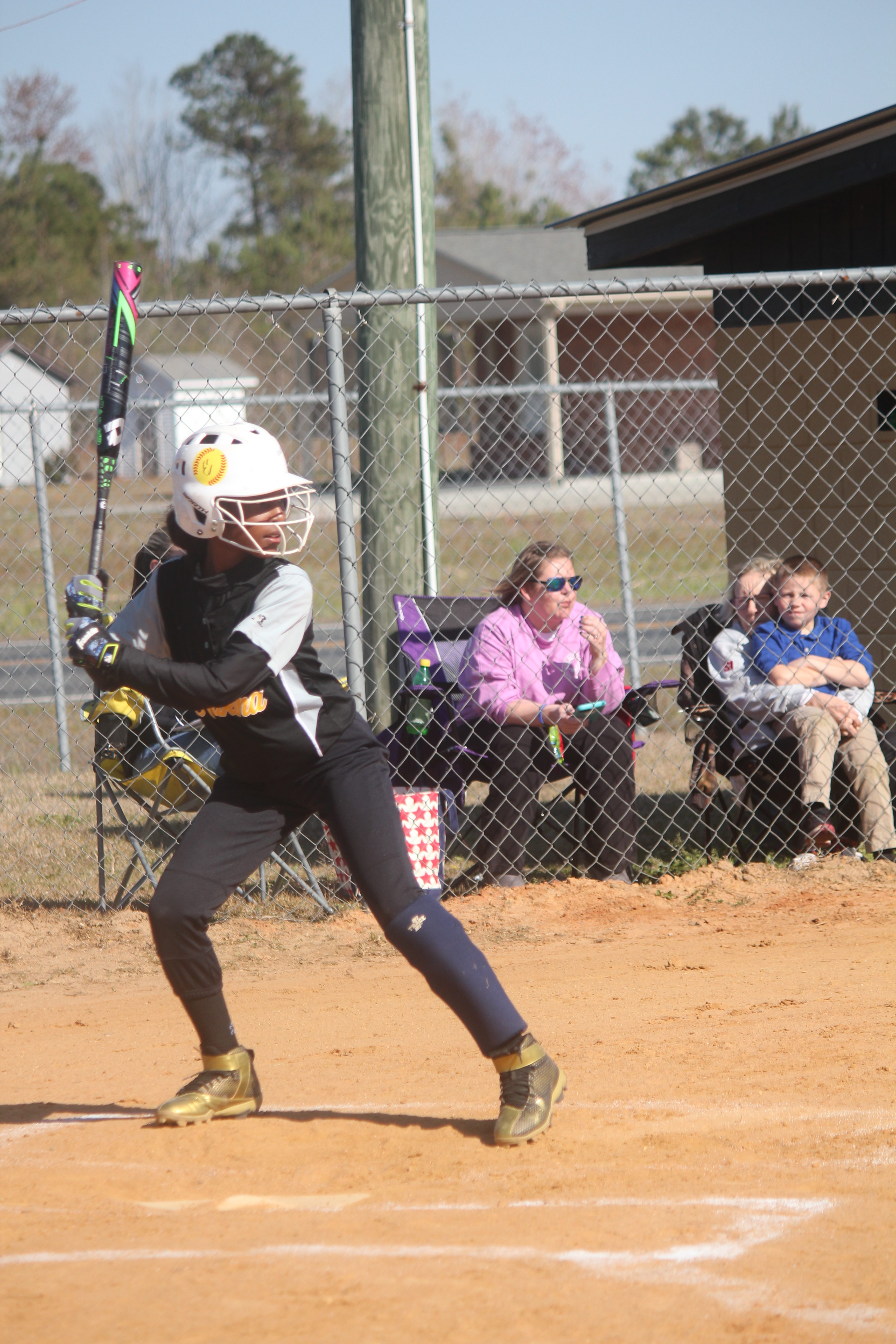 Woman swinging bat at softball during game.