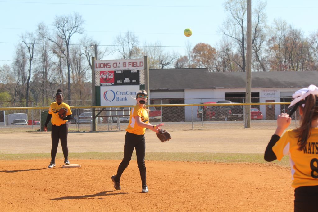 A softball team playing on the diamond, running, throwing, and catching the ball during a competitive game.