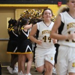 A group of girls in uniform walking down a basketball court