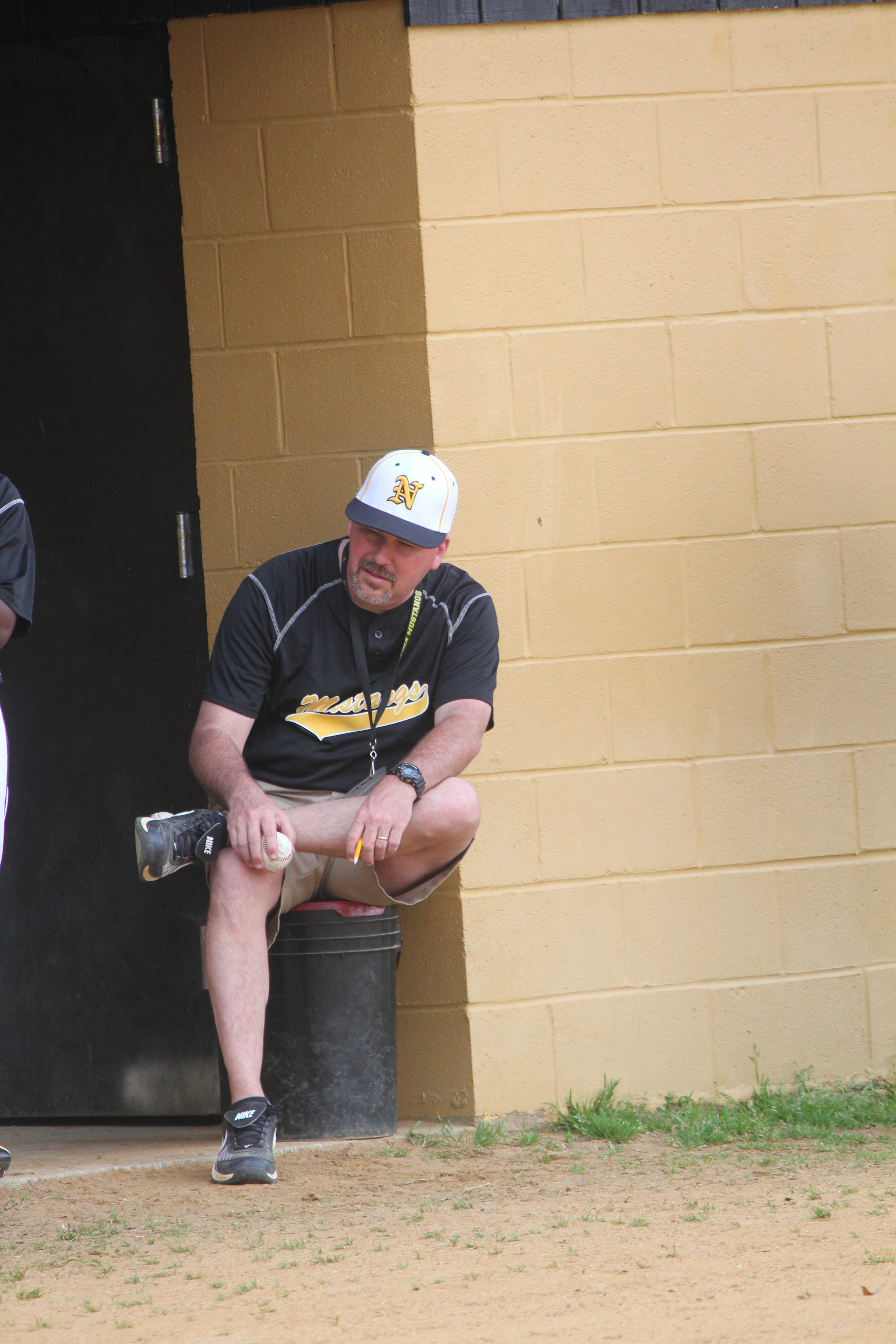 A guy  wearing his baseball uniform while sitting on a chair.