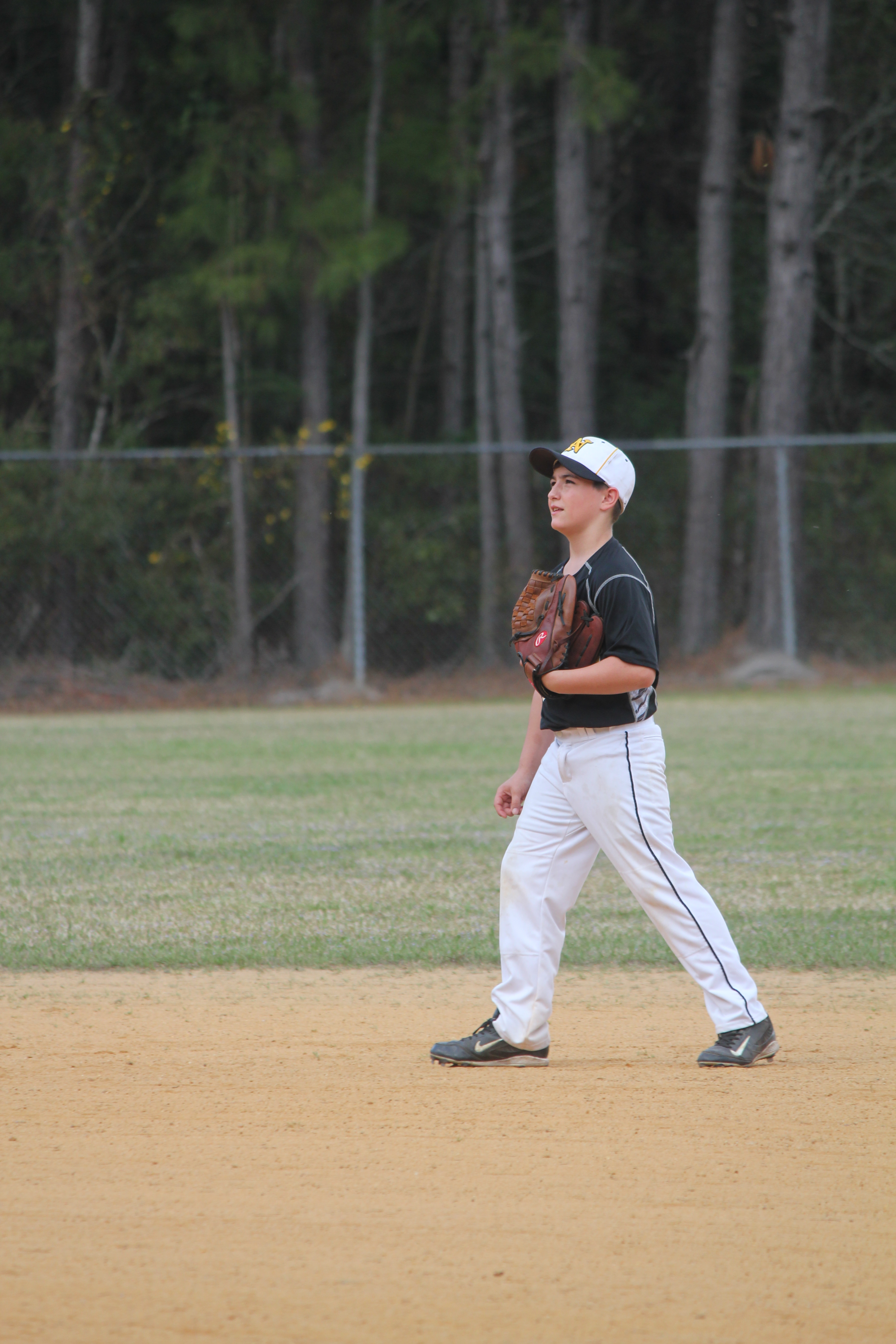 A young boy in a baseball uniform standing on a field, ready to play ball.