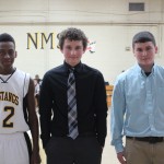 Three boys in ties standing in a gym.