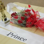 A bouquet of flowers on a table with a crown and a sign that says prince.