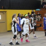 Group of girls playing basketball in school gym.