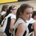 Girls basketball team sitting on bench during game.