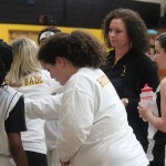 Group of girls in white shirts and black shorts standing together.