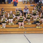 Group of cheerleaders in uniform sitting on bleachers.