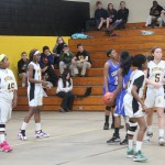 Group of girls playing basketball in school gym.