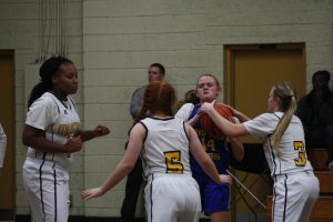 Young female basketball players in action on the court during a game in a gymnasium.