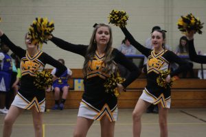 Cheerleaders in uniform performing energetic routine on basketball court during game.