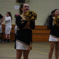 A cheerleader posing in front of a team of cheerleaders.