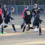 Young boys playing soccer on field.