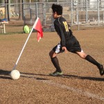 Young boy playing soccer on field.