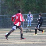 Young boy playing soccer on field.