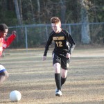 Young boys playing soccer on field.