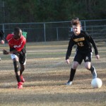 Young boys playing soccer on field.