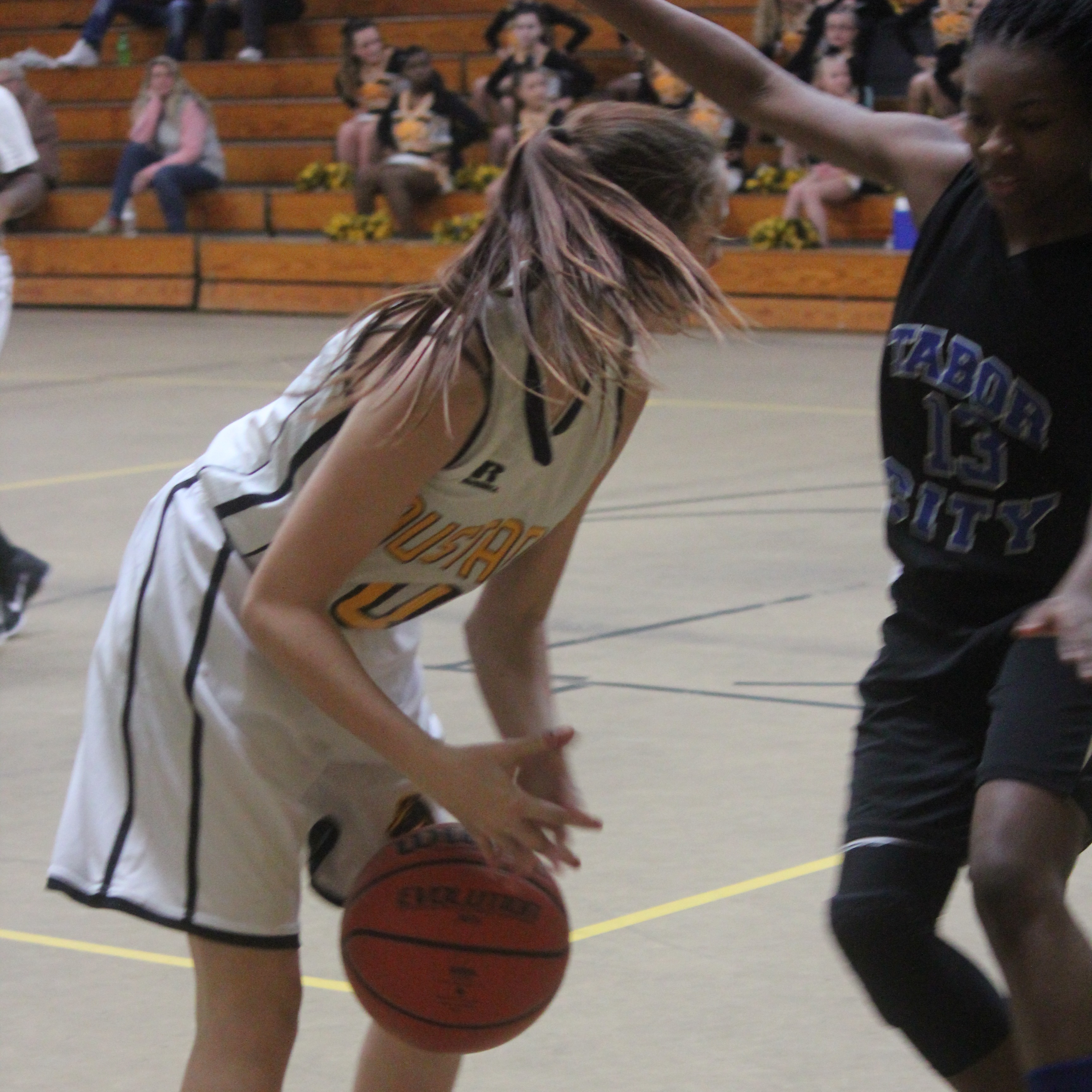 Young girl dribbling basketball on outdoor court.