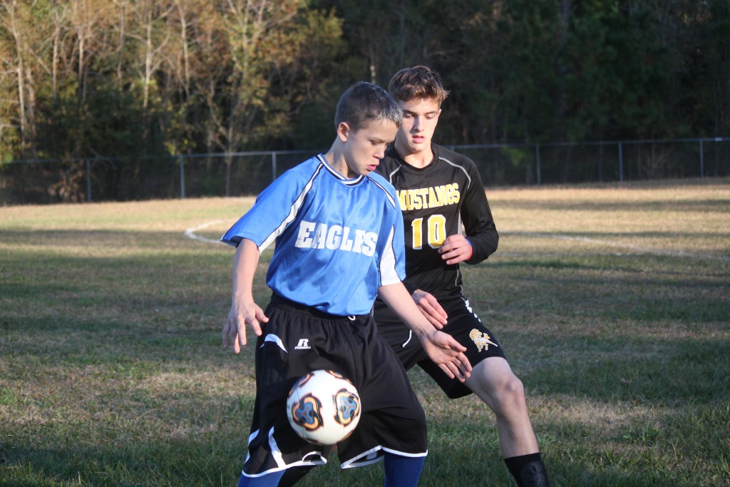 Young boys playing soccer on field.