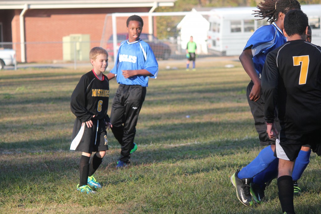 Young boys playing soccer on field.