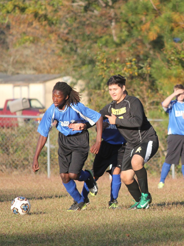 Young boys playing soccer on field.