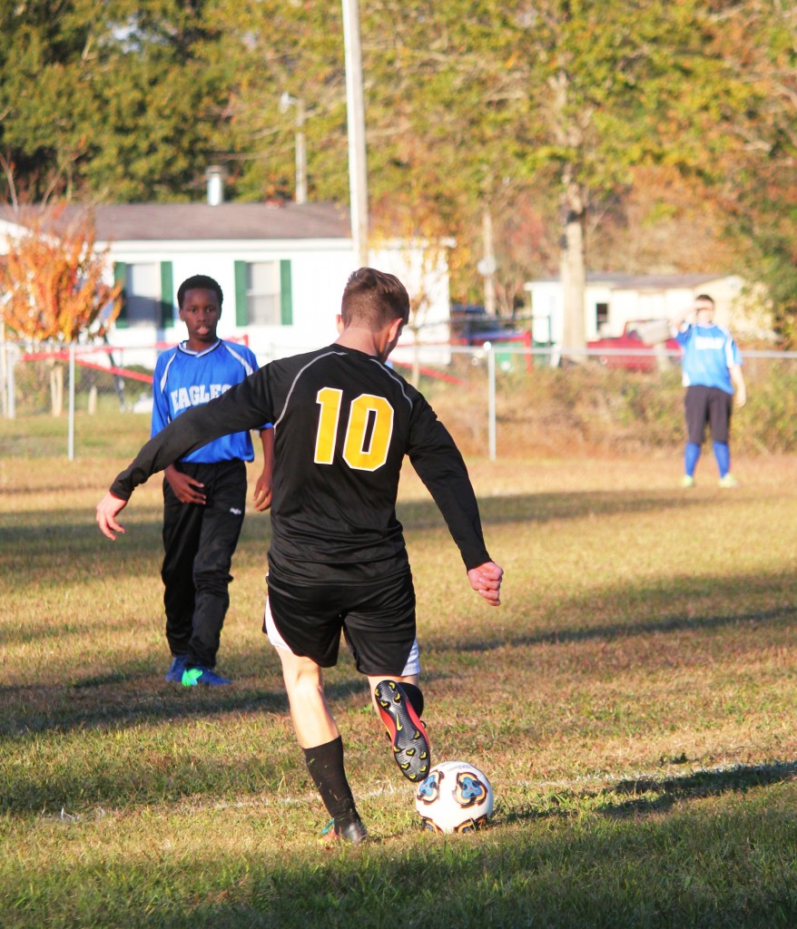 Young boys playing soccer on field.