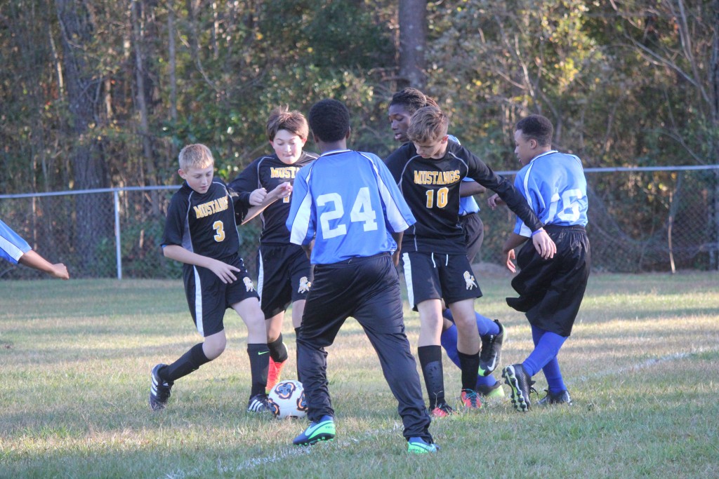 Young boys playing soccer on field.