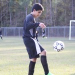 Young boy playing soccer on field.