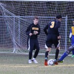 Young boys playing soccer on field.