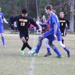 Young boys playing soccer on field.