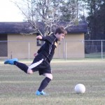 Young boy playing soccer on field.