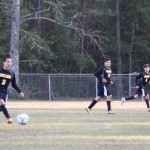 Young boys playing soccer on field.