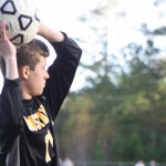 Young boy playing soccer on field.