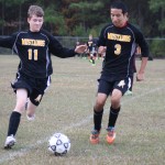 young boys playing soccer on a field.