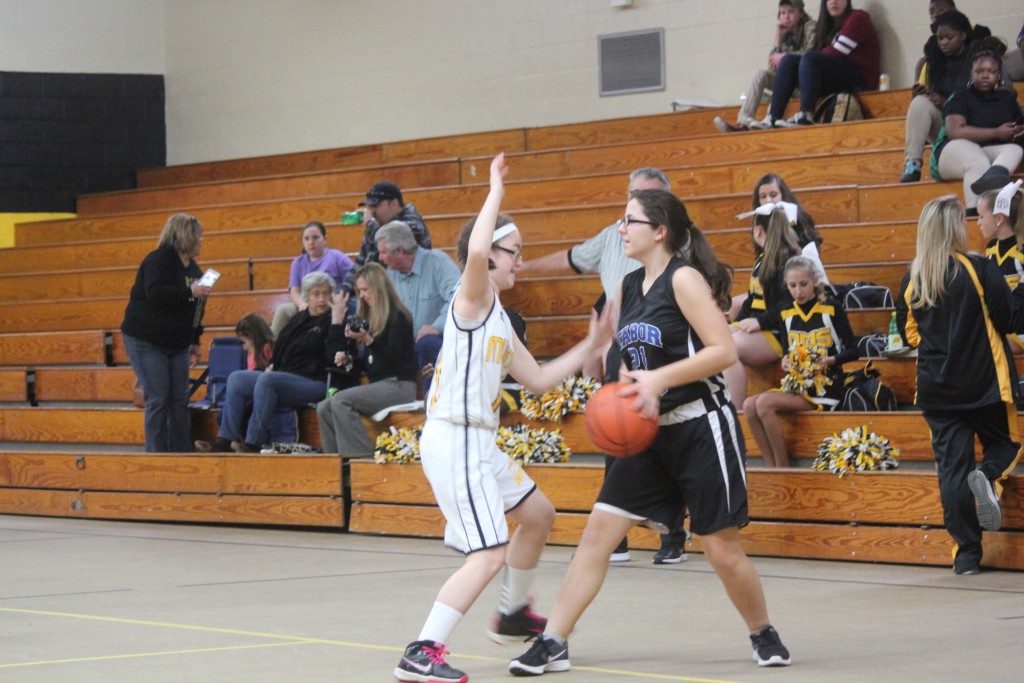 A girl in a black and white uniform attempting to block a shot during a sports game.