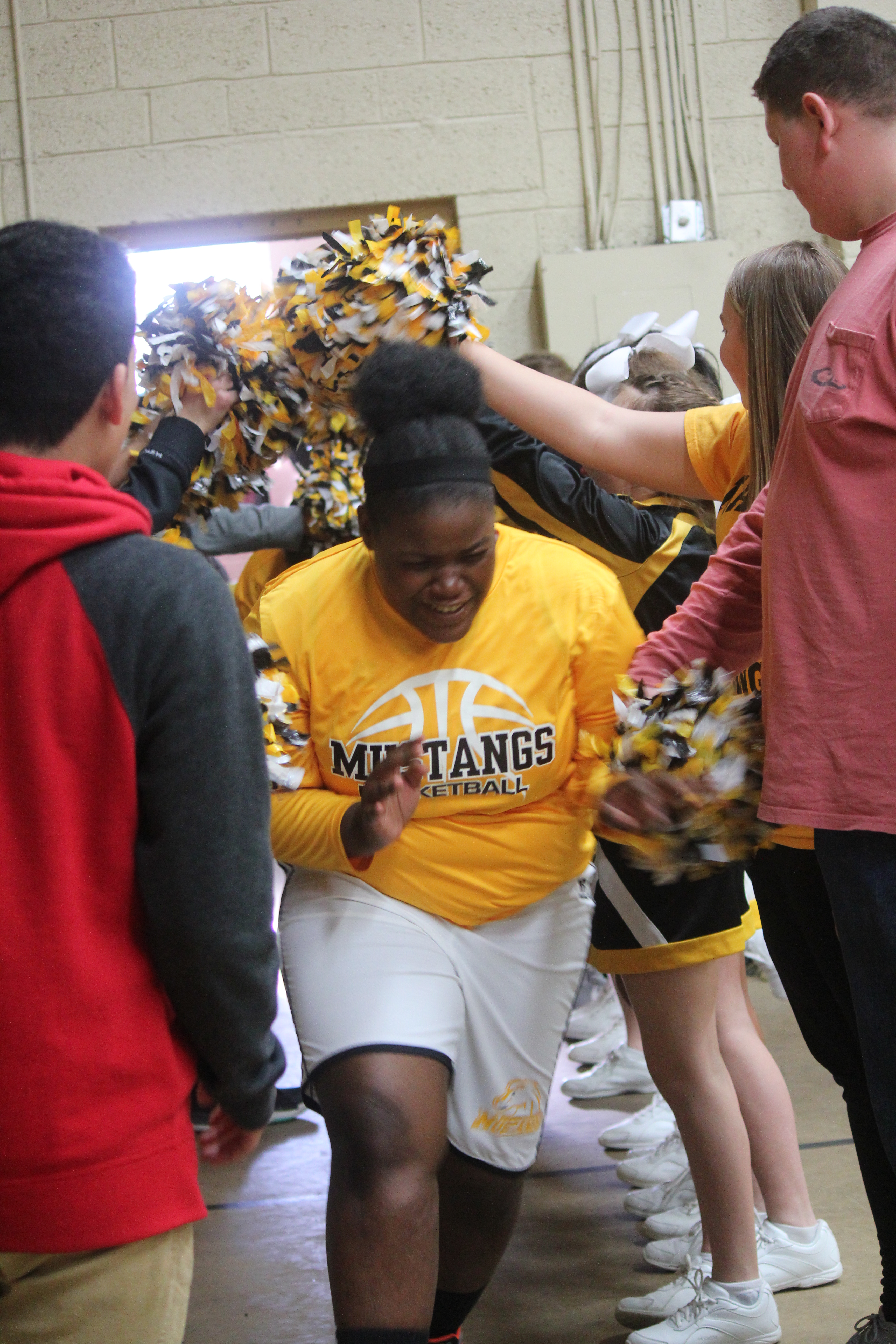 Gym-goers surrounded by cheerleaders, creating a lively atmosphere in the fitness facility.