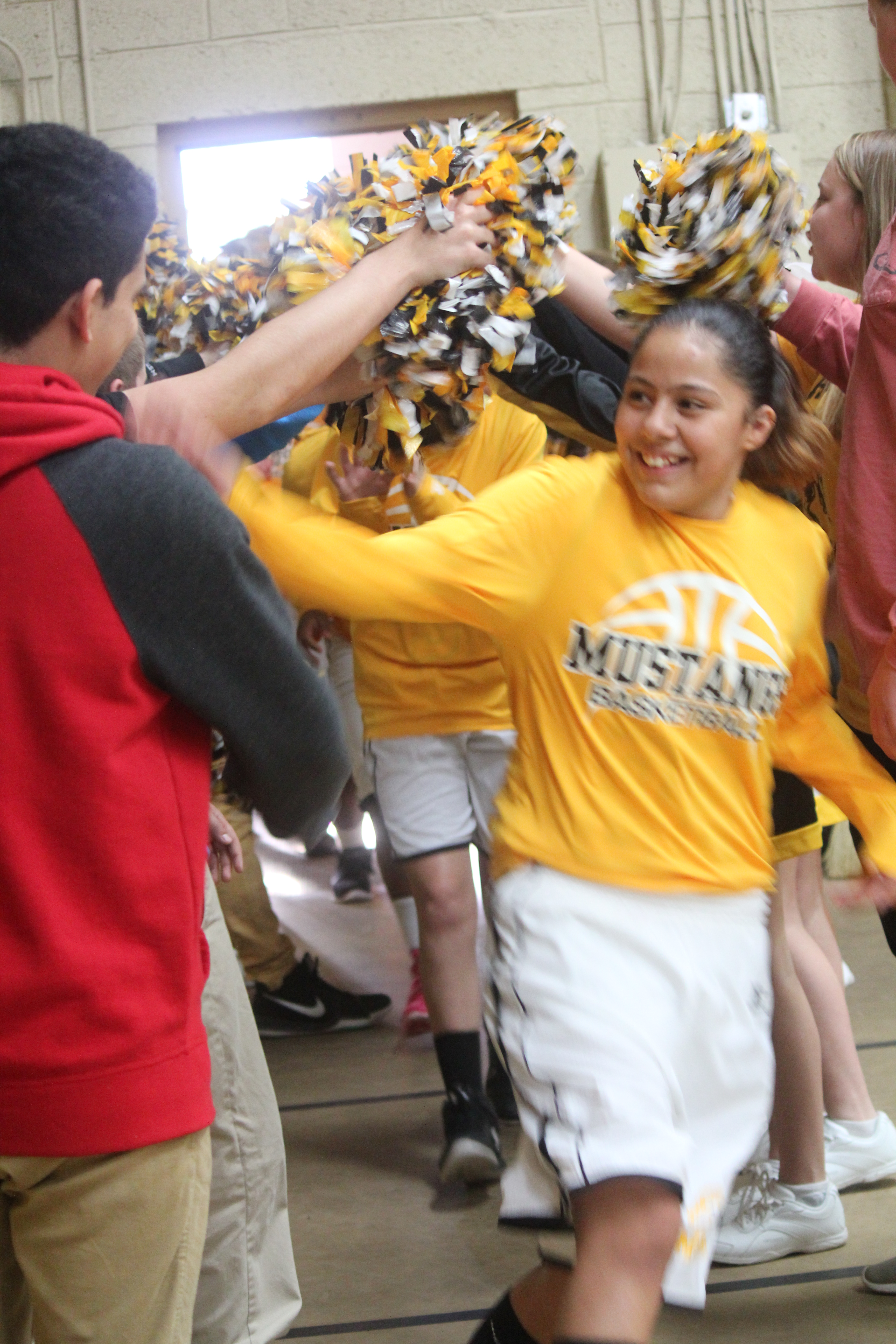 Gym-goers surrounded by cheerleaders, creating a lively atmosphere in the fitness facility.