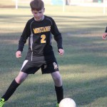 A young boy playing soccer on a field.