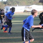 young boys playing soccer on a field.